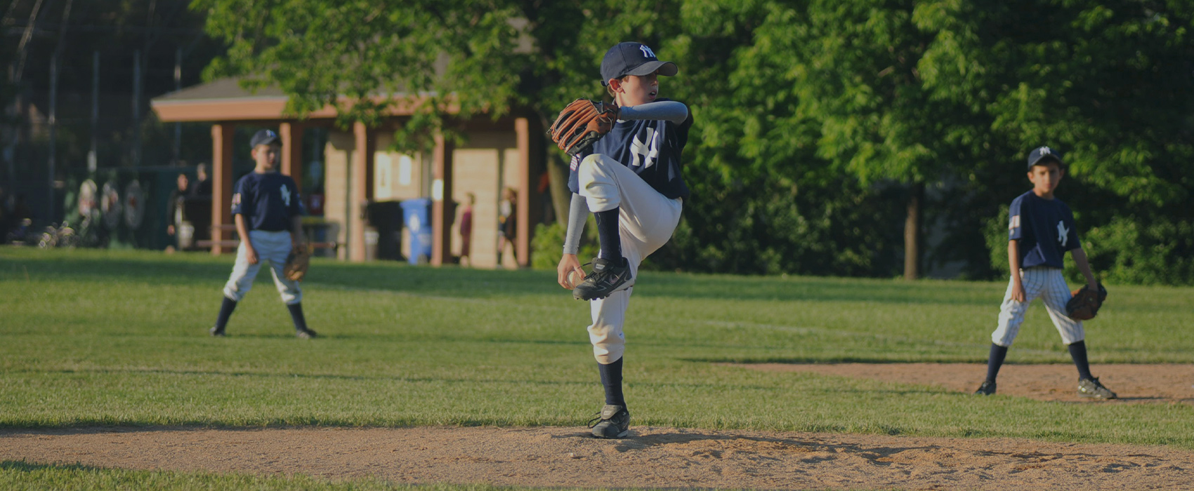 A young baseball player is winding back to throw a pitch.